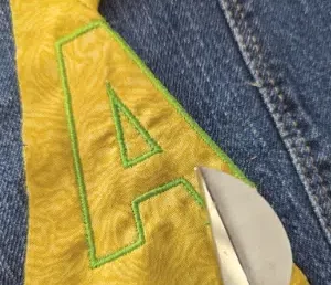 lettrine fablab. Aen tissu jaune appliqué sur du Jean. contour brodé à la machine.
