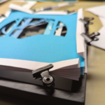 Vue d'un kirigami en cours de montage dans un cadre : les accordéons sont tenus par des pinces.
