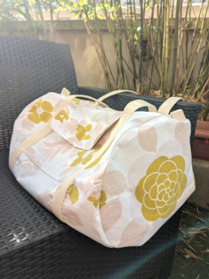Sac polochon à partir d'une nappe. Fond blanc, motifs à fleurs rose pale et vert kaki.